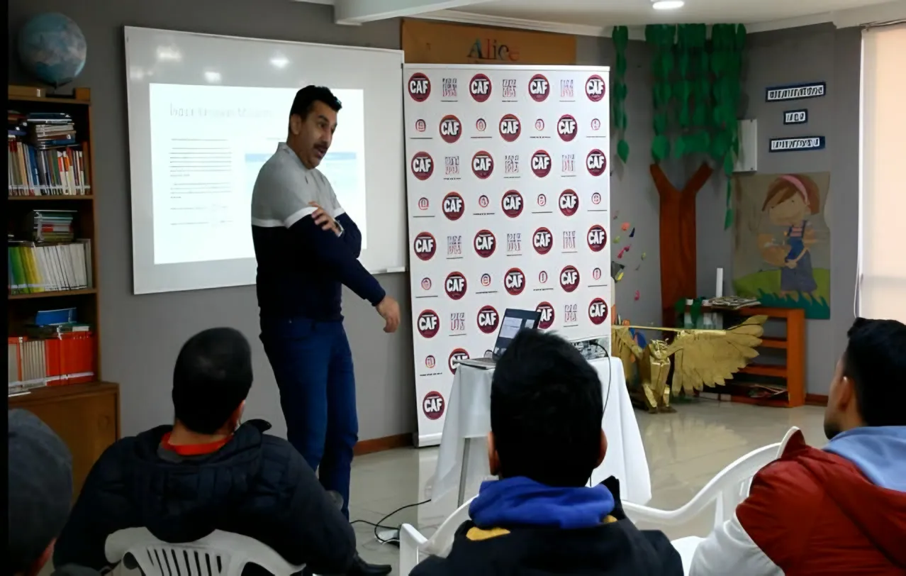 Capacitación de cineantropometría: un expositor frente a una proyección y asistentes sentados.