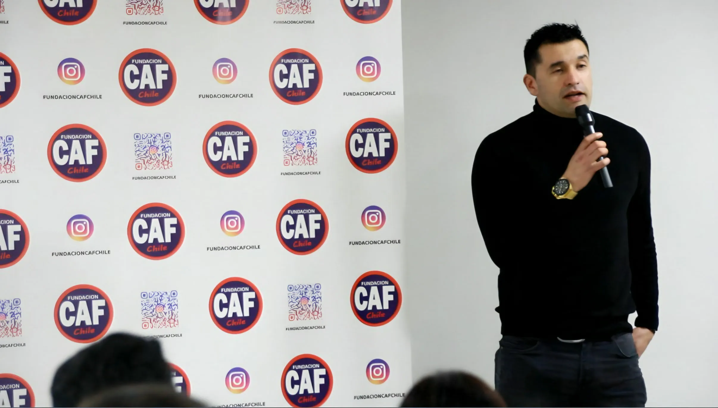 Sebastián Ahumada habla con micrófono frente al telón de la fundación.